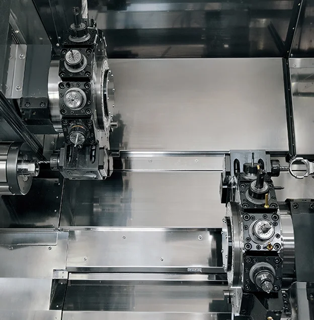 Intérieur d'une machine-outil CNC avec deux tourelles et pièces métalliques usinées